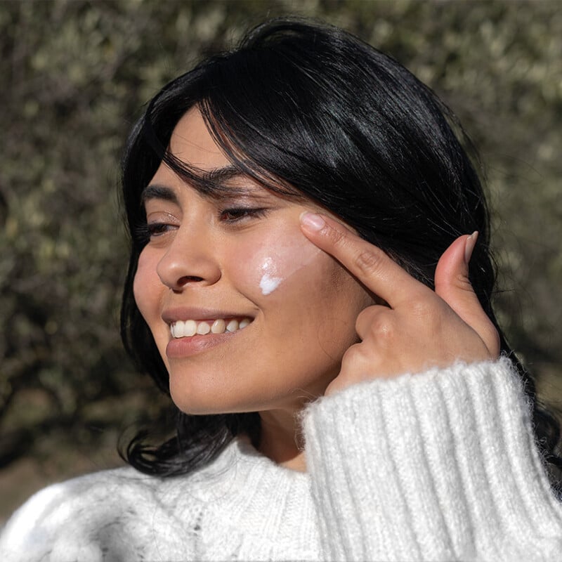 young woman applying the nourishing face cream