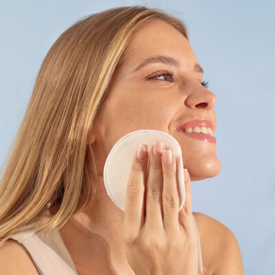 young woman removes make-up with a reusable cotton pad