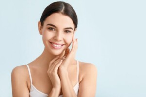 femme souriante qui touche son visage à peau grasse